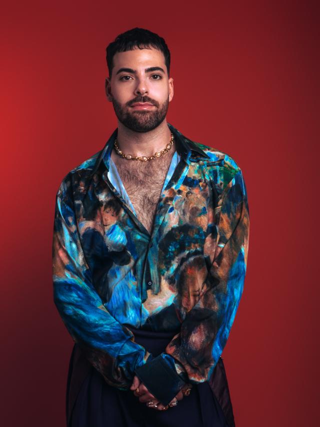 man in animated top in front of red backdrop