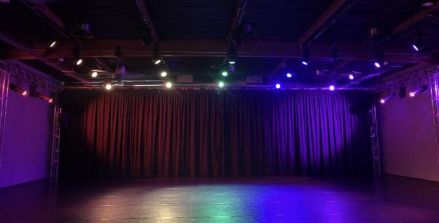 rainbow lights in a black space with a curtain