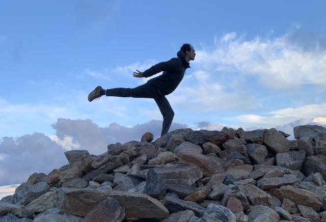 person in dance pose on mountain of rocks