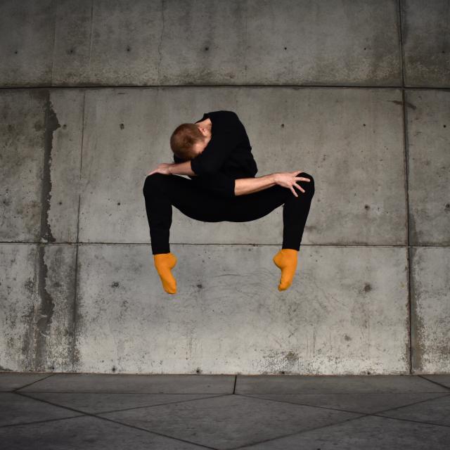 dancer in black outfit, yellow socks jumping 