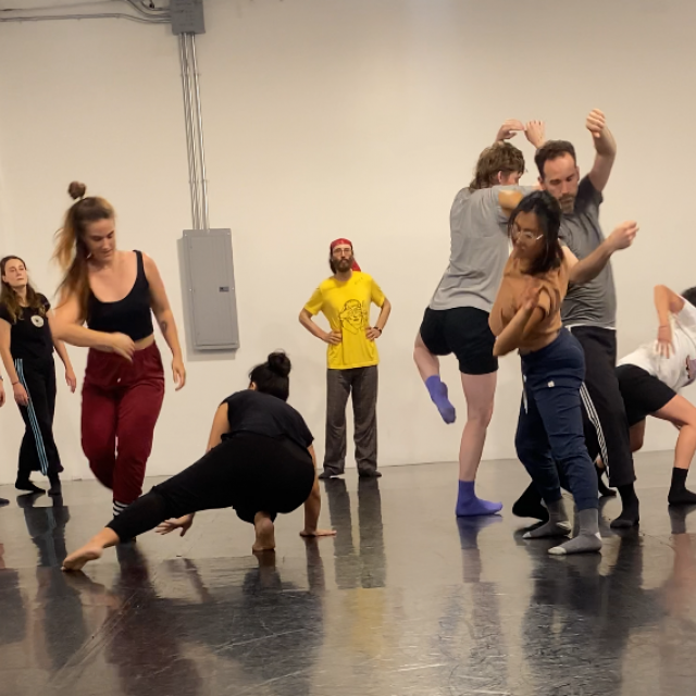 group of people moving close to each other in different positions in a white room